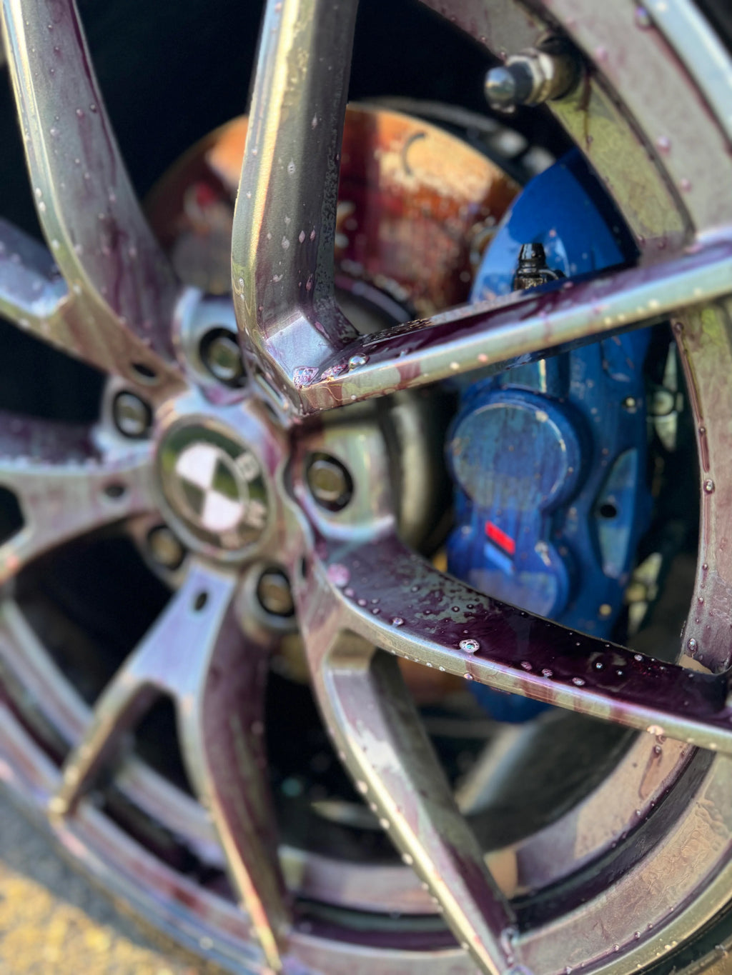 Close-up of a car wheel with applied wheel cleaner showing purple cleaning solution.
