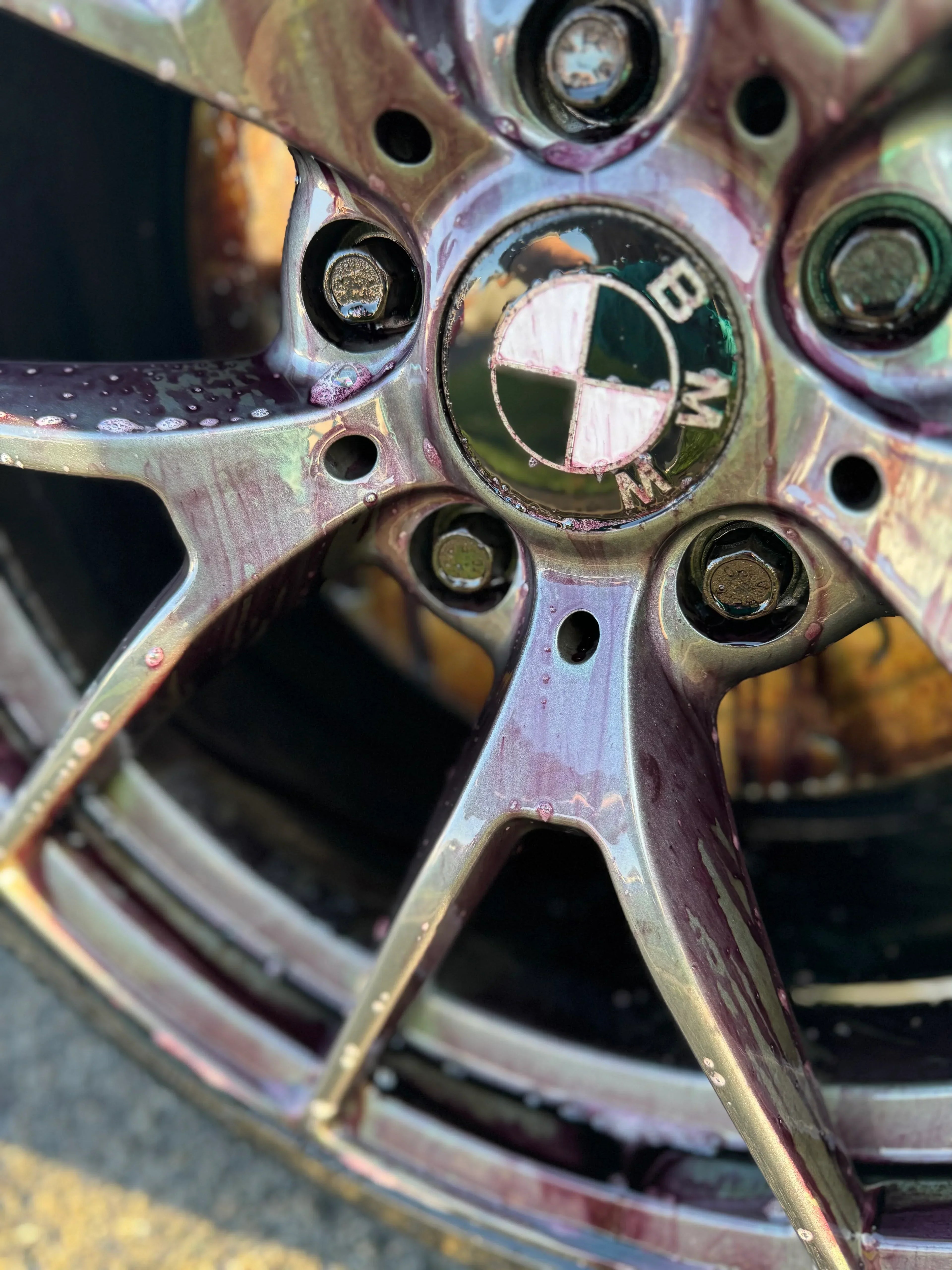 Close-up of a BMW wheel with car wheel cleaner and dirt being rinsed off