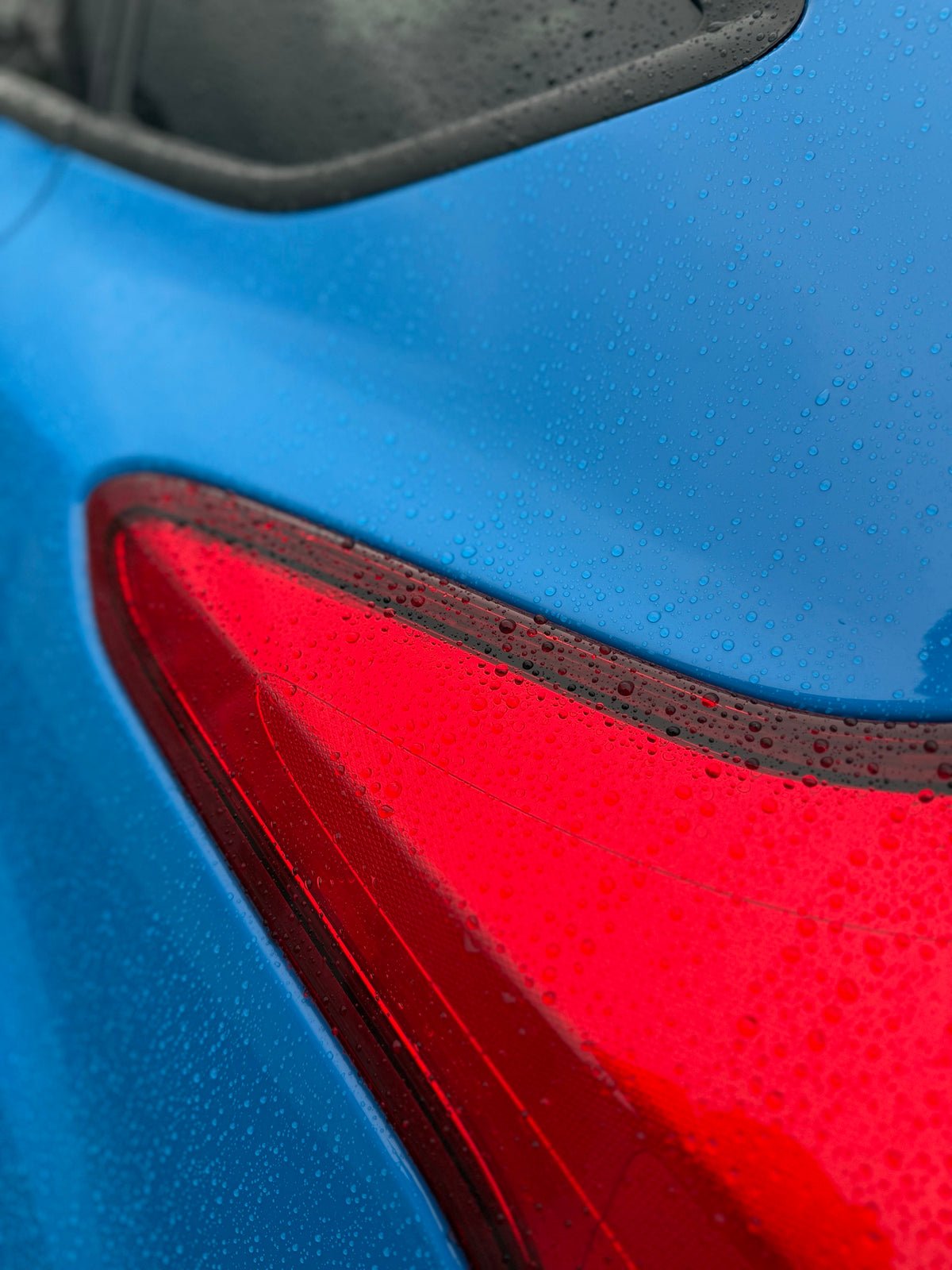 Water beads on blue paintwork and a red tail light after Pure Gloss Pro 9H ceramic coating